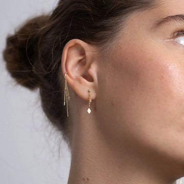 model wearing gold dangly earrings