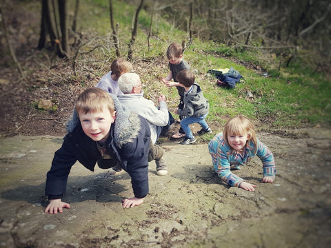 Children climbing rock in woods