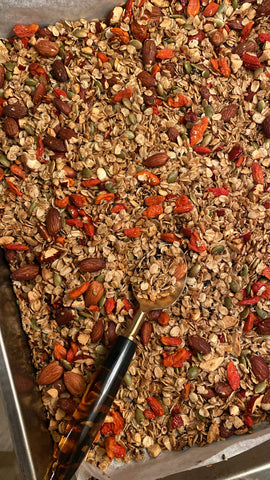 Toasted granola with goji berries, red dates, black sesame and other ingredients in a baking tray.