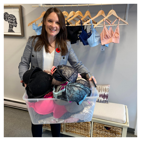 Shauna Allan at Modern Match Lingerie holding a bin of bras that were donated by the community