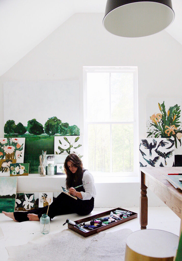 Natalie Hamm surrounded by painting supplies and canvases