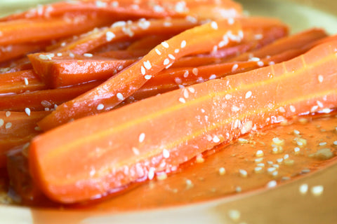 close up of roasted carrots topped with sesame seeds and honey
