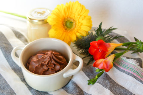chocolate mousse in a white ramekin with yellow and red flowers on a blue and white stripped tea towel