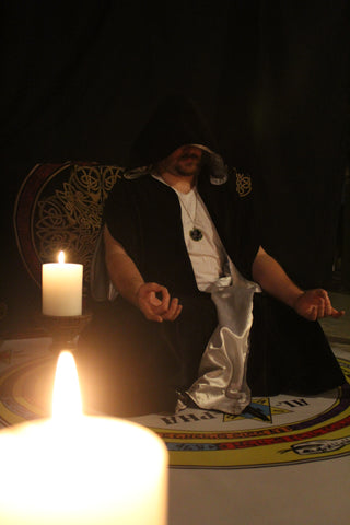 A sorcerer seated on a summoning circle surrounded by candles ready to evoke demons.