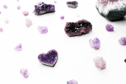 Amethyst crystals of various sizes scattered on a white surface.