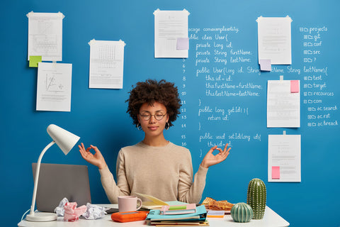 Woman in a meditative pose at her office desk.