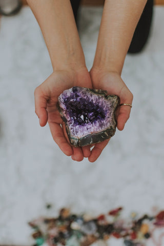 Amethyst crystal is being held in model's hands.