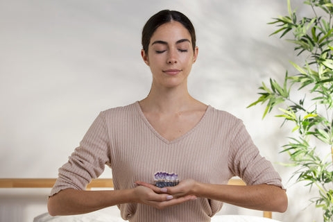 Model holds an amethyst crystal while practicing meditation.