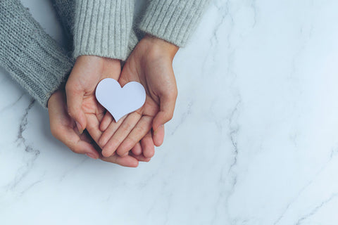 Couple holds paper heart.