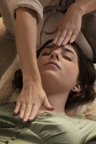 A young woman undergoing a Reiki healing session with her therapist.