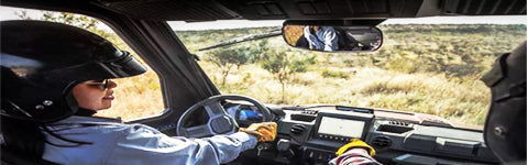 two people inside a utv looking at a rear view mirror