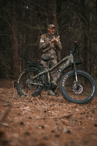 Jason Say using his eBike for turkey hunting – standing behind the bike using a turkey box call.