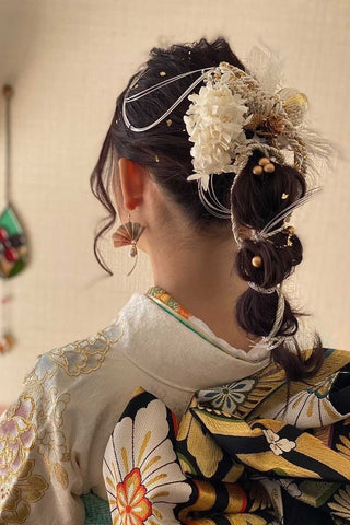 A woman in a white kimono celebrating a coming-of-age ceremony wearing a fan-shaped kimono accessory
