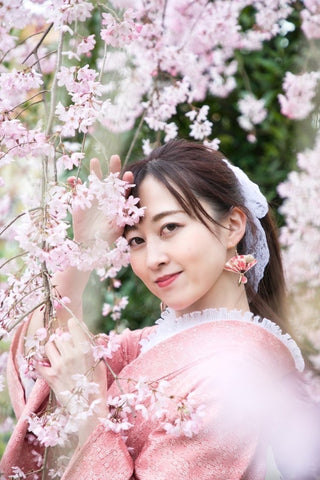 満開の桜に良く似合うピンク色の和紙アクセサリーを身につけた着物美人