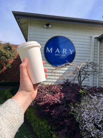 takaway coffee cup held in front of Mary Eats Cake