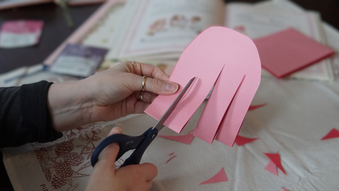 Piper and Leaf crafter cutting to the left of the middle cut on the rounded paper for a DIY galentine valentine craft