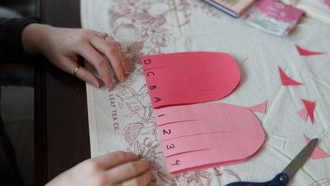 Piper and Leaf crafter labeling each stip of paper for a galentine valentine craft