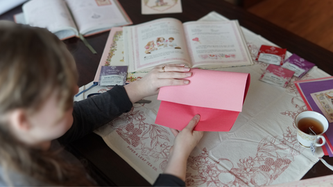 Piper and Leaf crafter folding pink and red paper for a galentine valentine DIY craft