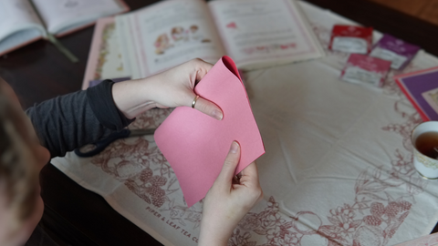Piper and Leaf crafter folding paper in half for a DIY galentine valentine craft