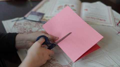 Piper and Leaf crafter cutting folded paper in half for a DIY galentine valentine craft