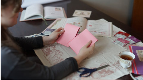 Piper and Leaf crafter holding two cut pieces of paper for a DIY galentine valentine craft