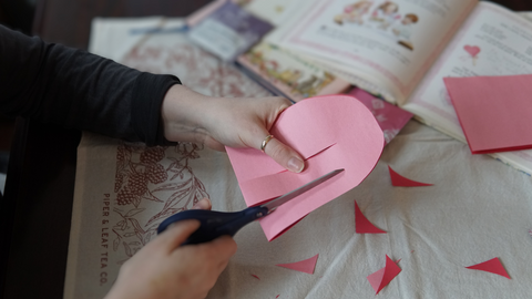 Piper and Leaf crafter cutting to the right of the middle cut on the rounded paper for a DIY galentine valentine craft