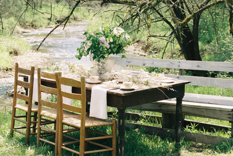 A table decorated with festive spring decor by a river, set for a Spring tea party, DIY idea
