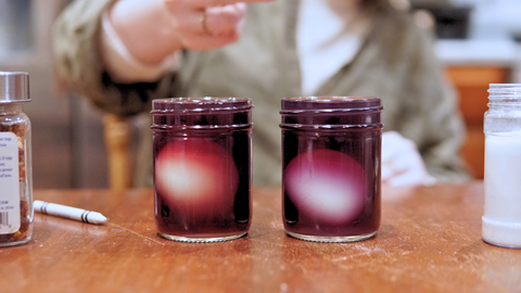 Piper and Leaf employee showing 2 eggs in a Strawberry Shindig tea dye bath for a fun DIY Easter craft