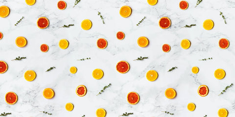 A collection of orange slices and herb sprigs across a marble countertop
