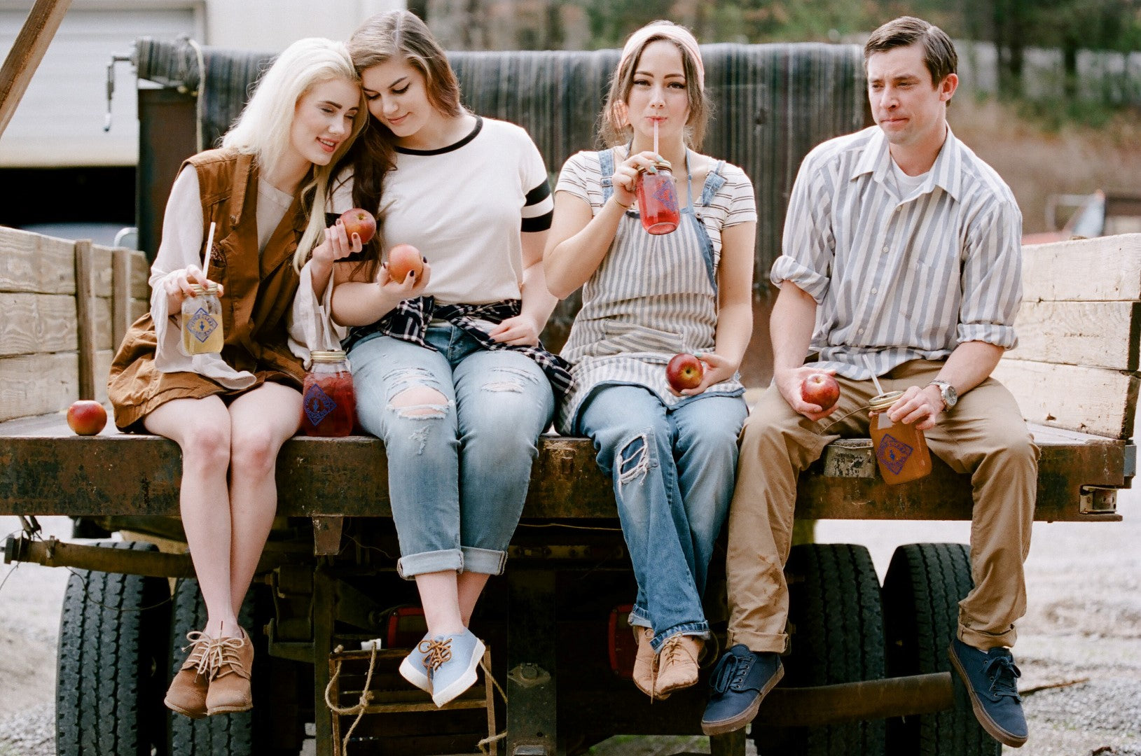 Four fans of Piper and Leaf holding jars of iced cold Orchard Peach tea. Laughing and celebrating the joys of community and good, refreshing tea from Piper and Leaf