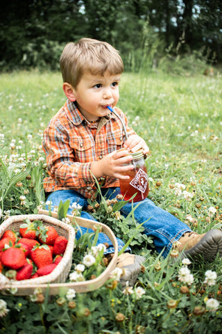 Little boy sipping on some Strawberry Shindig in an open field