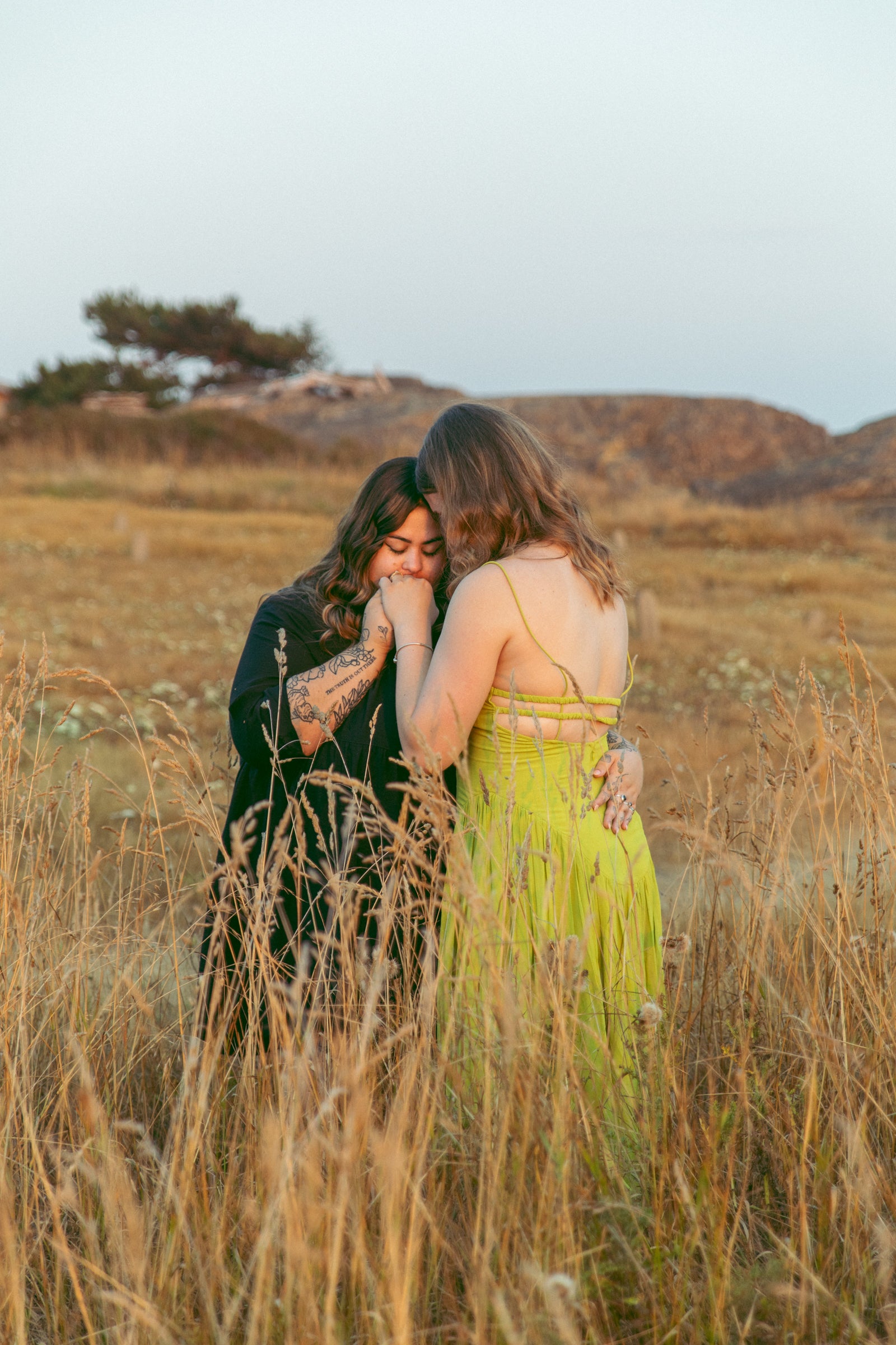 Series of photographs capturing Yolanda and Zoe embracing in a field of tall grass, their love evident in each shot. Against the backdrop of nature, their bond shines through in tender embraces and shared moments. Photography by Bertie, specializing in capturing authentic connections and emotions in Victoria's scenic landscapes.