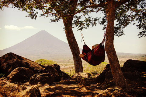 person laying in hammock near a mountain