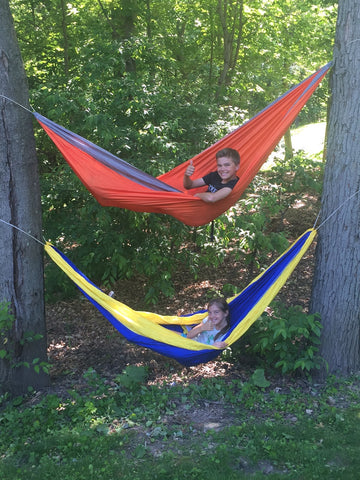 one person in a hammock that is hanging above another person in a separate hammock