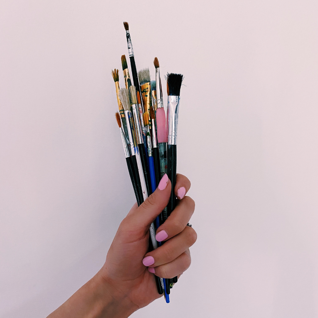 hand holding multiple paintbrushes