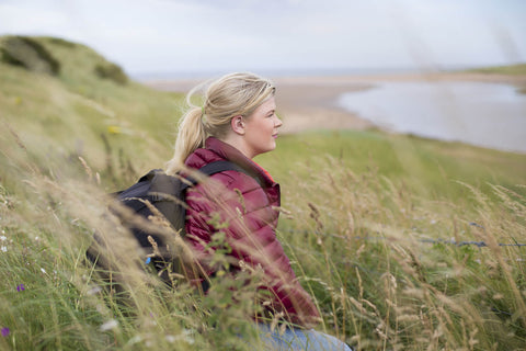 Woman taking a rest from her hike on a hillside and enjoying the view