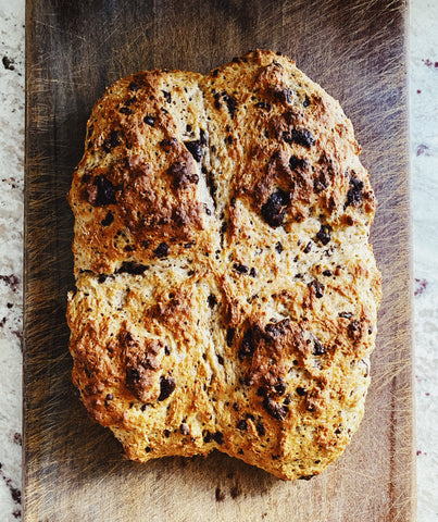 A craggy-topped loaf of Irish soda bread on a wooden board.
