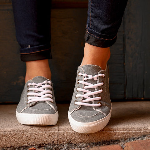 Zapatos grises con cordones blancos sin atar