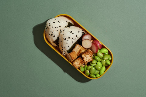 onigiri bento box lunch with lima beans, grapes, and other sides