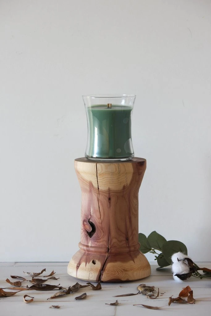 木质烛台上有一支装在透明玻璃小杯里的绿色蜡烛