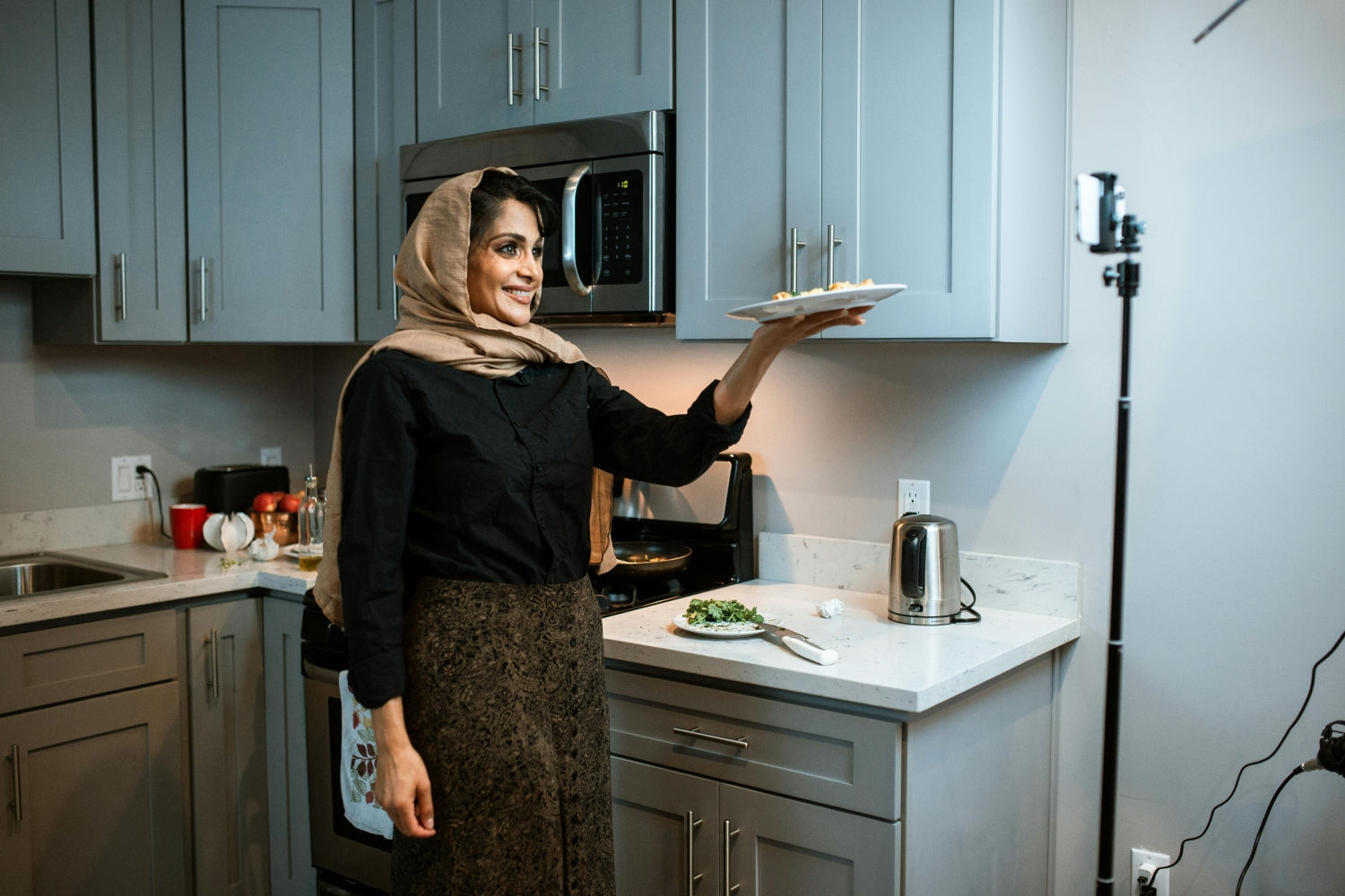 一个戴着头巾的女人在厨房里端着一盘菜自拍社交媒体视频