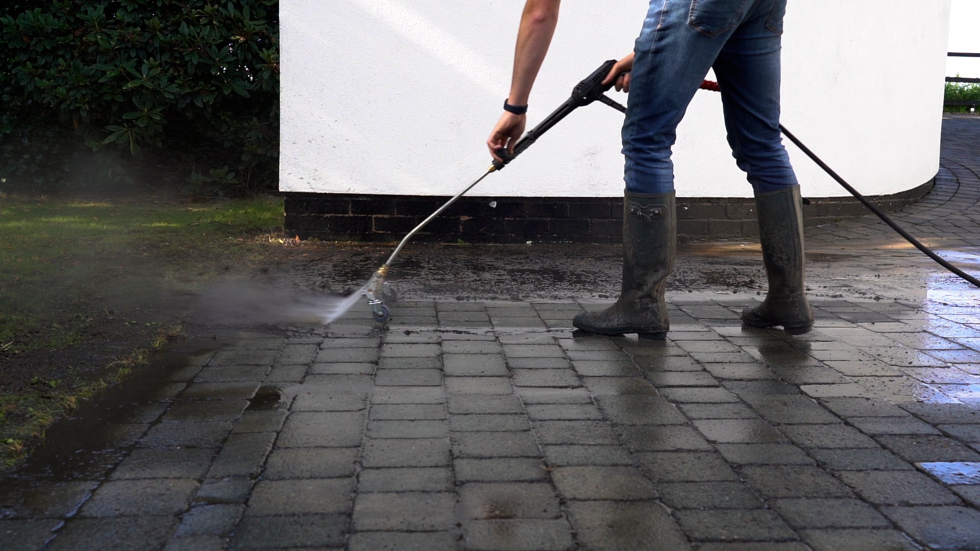 Photograph of man pressure washing muddy patio 