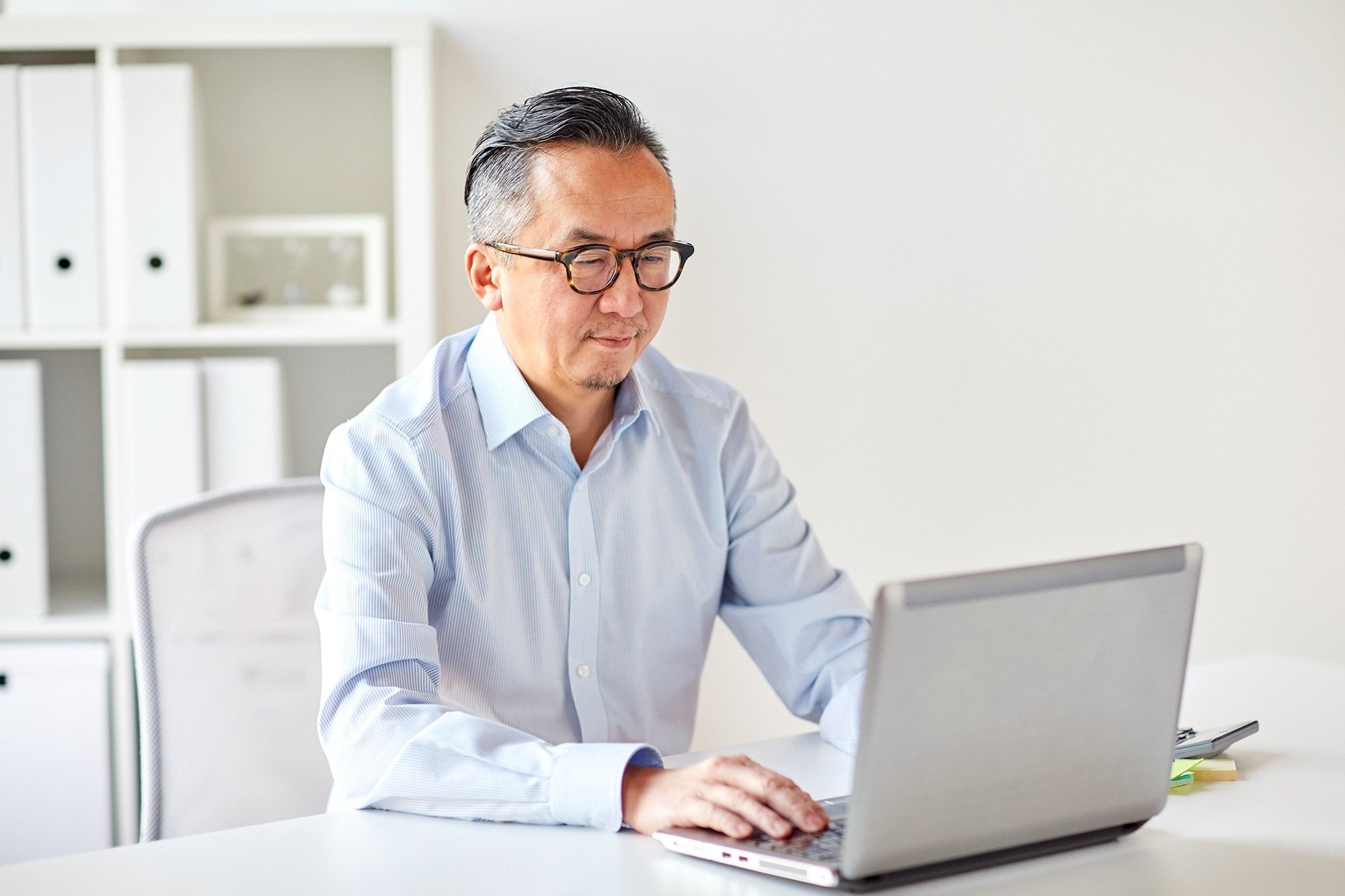 A man sitting at his computer with reading glasses on