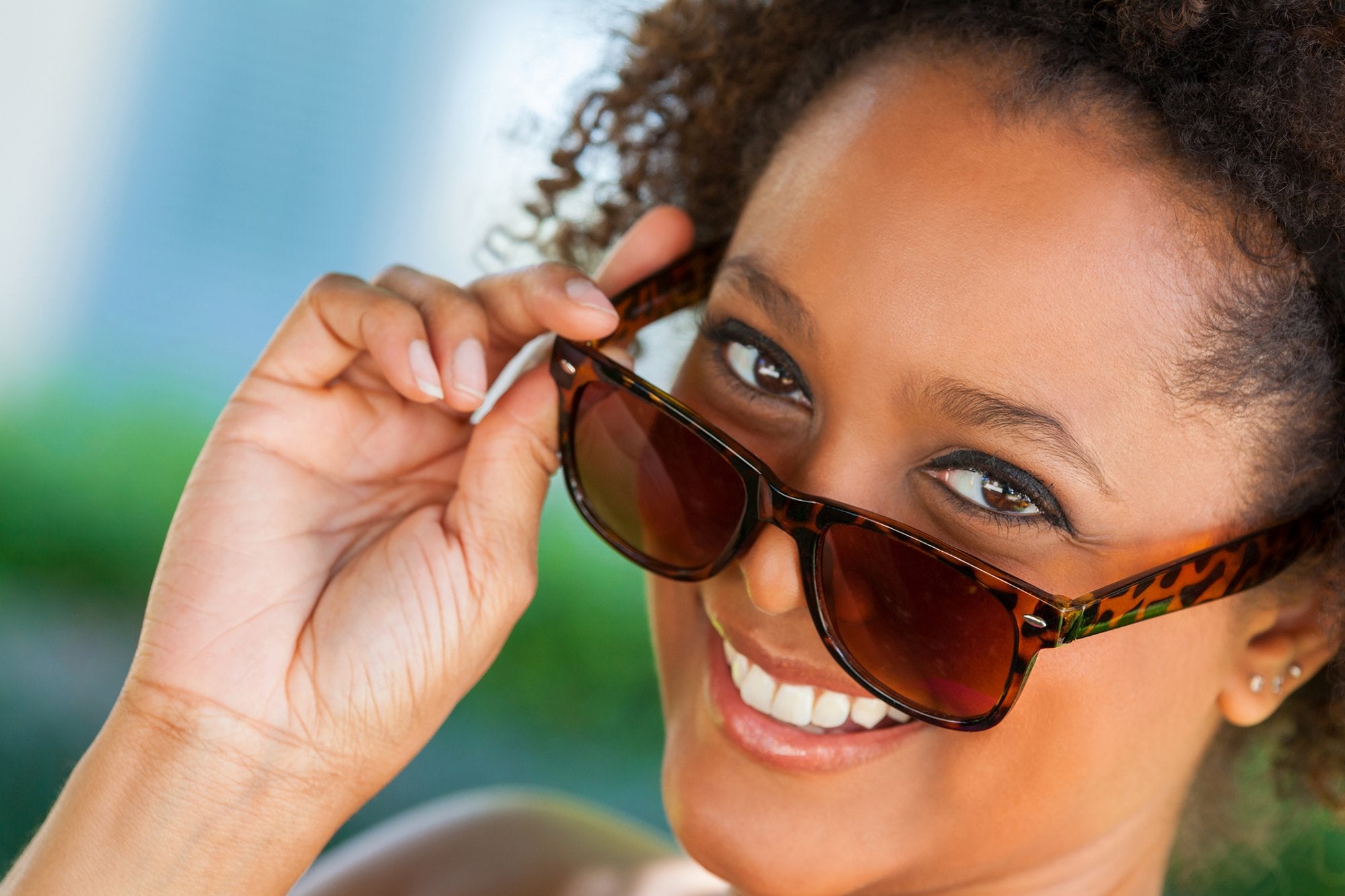 A woman lowering her sunglasses showing her eyes