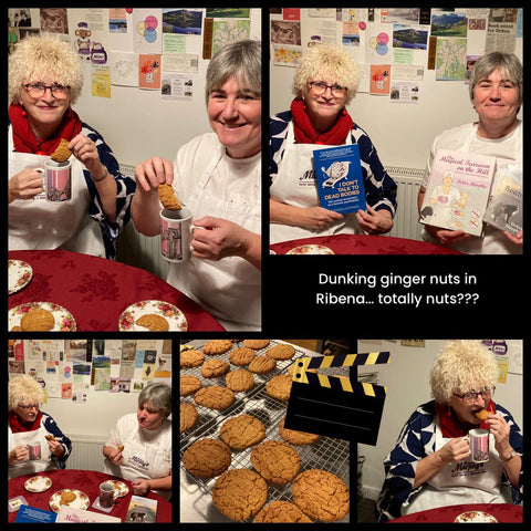 Two women showing books and eating gingernuts