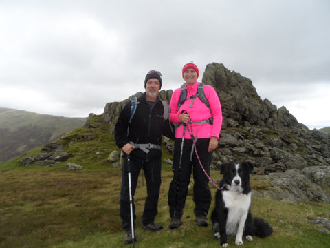 Man and lady standing on a hill with black and white Border Collie