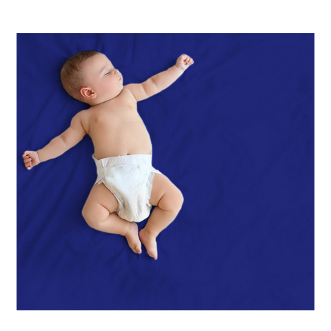 baby relaxing on dark blue polka tots dry bedsheet or bed protector.