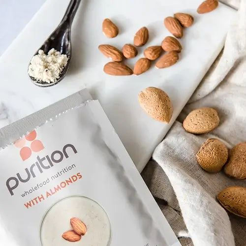 Purition Almond 40g sachet surrounded by whole almonds.