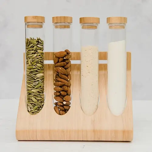 Test tubes in wooden stand with pumpkin seeds, almonds and protein powders