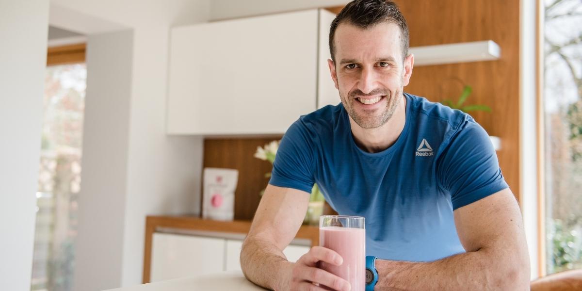 Personal trainer in kitchen drinking a Purition whole food meal shake.